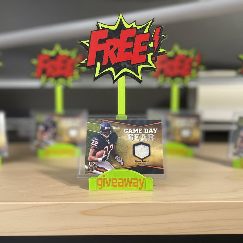 Trading card with 'Game Day Gear' on a table with 'Free Giveaway' signs in the background.