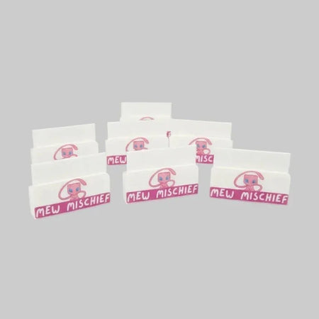 Multiple boxes of 'Mew Mischief' on a table with a 'Fruitrip Cards Supplies' mat.