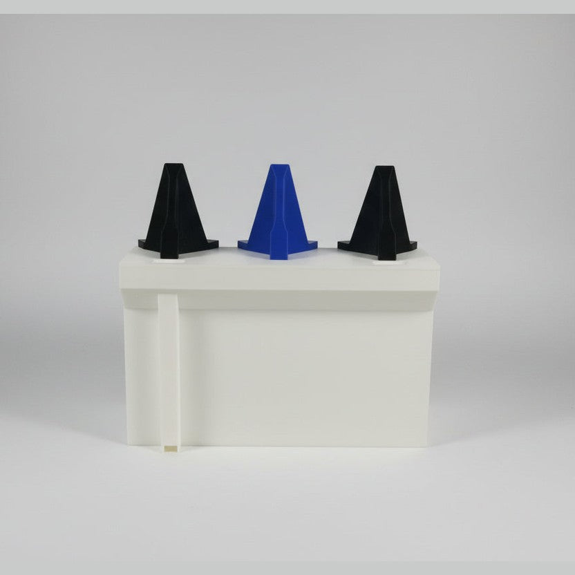 White cabinet with a blue tool on top against a dark wall