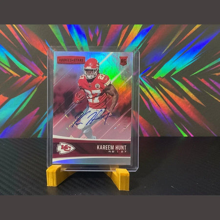 Trading card of a football player in a red uniform with a colorful background, held in a clear plastic holder.