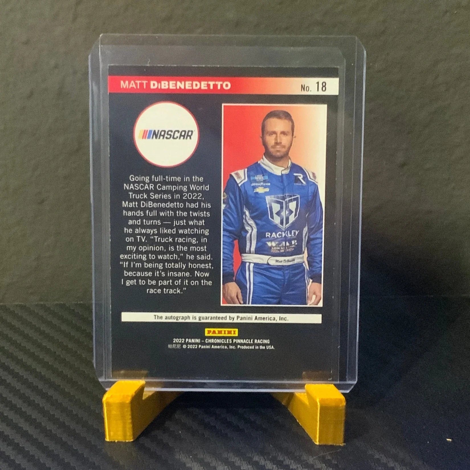 Trading card of a NASCAR driver in a clear plastic case on a textured surface