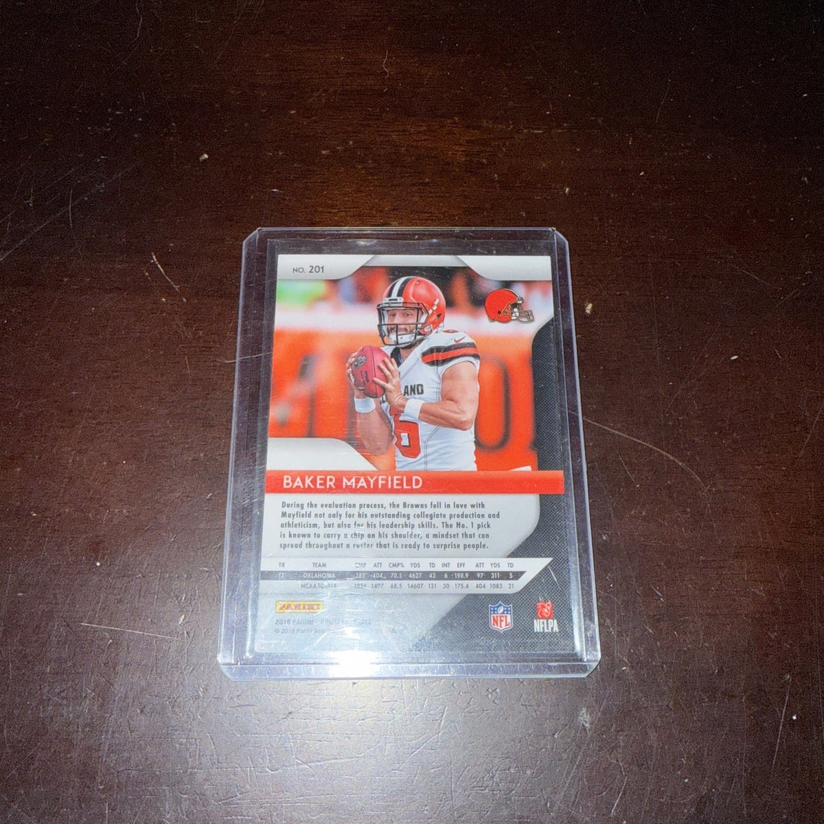 Trading card of a baseball player in a clear protective case on a dark surface