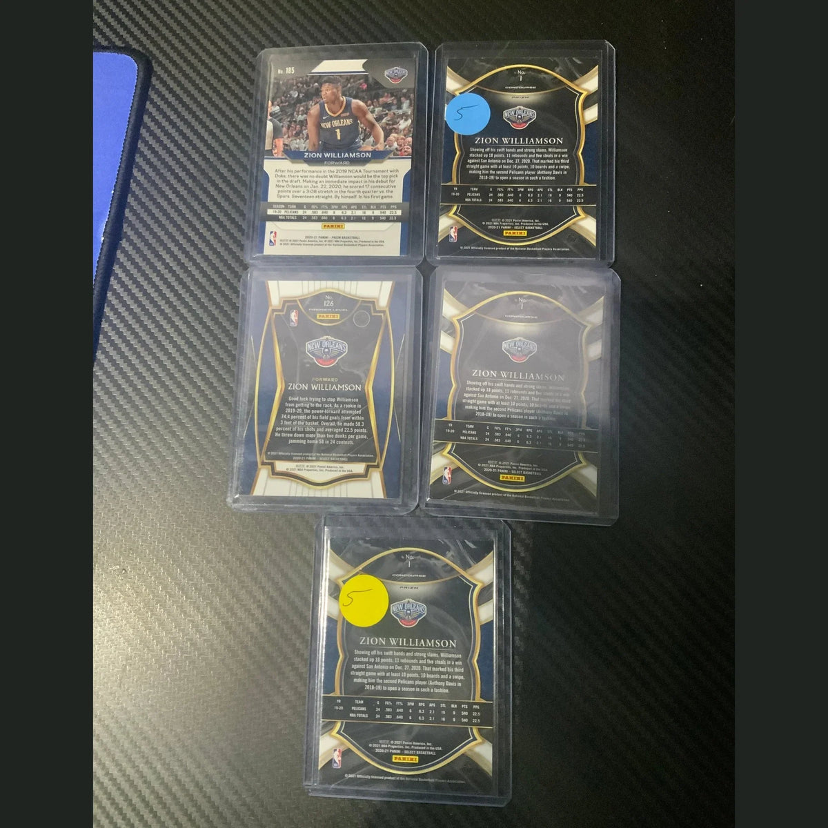 Collection of trading cards in protective cases on a dark textured surface