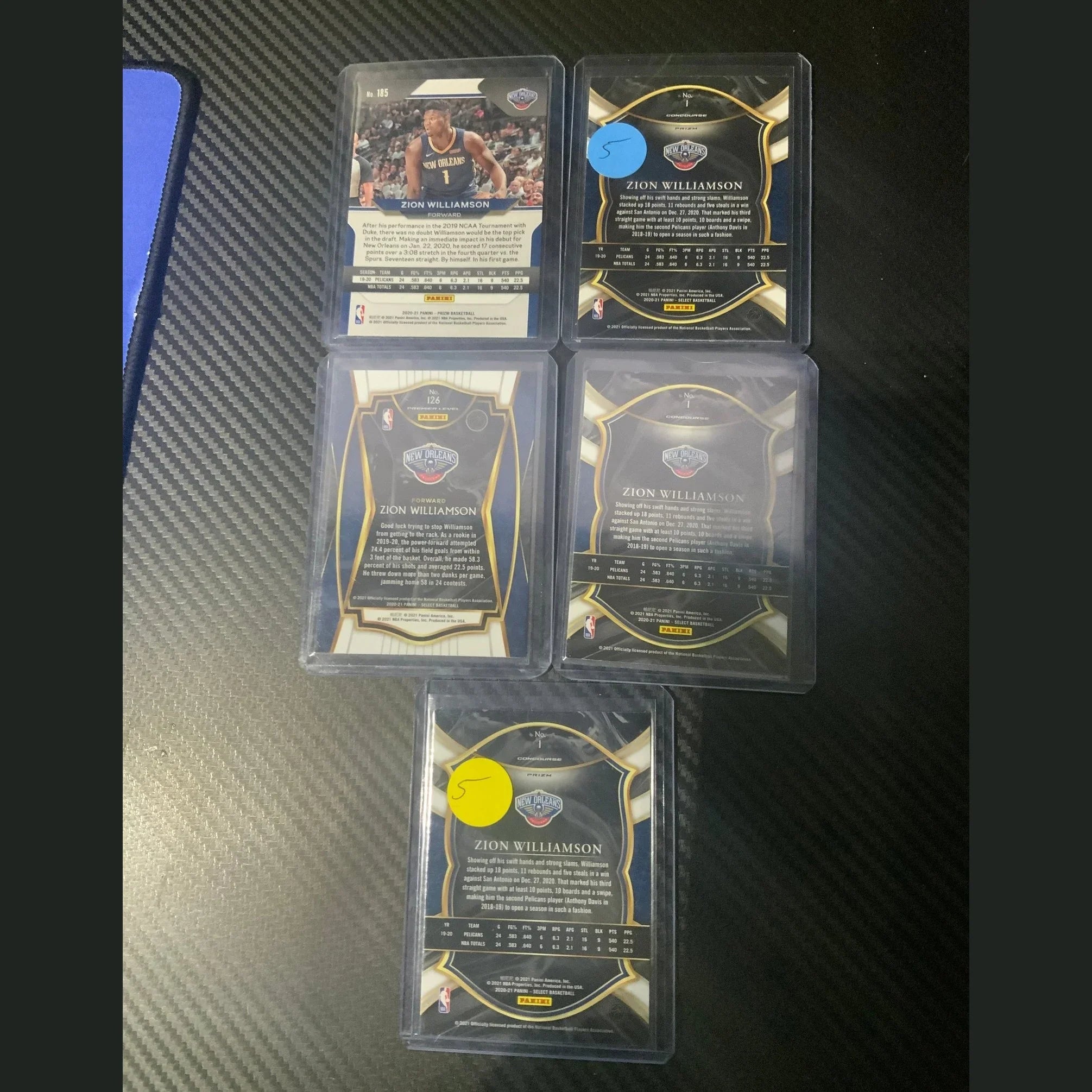 Collection of trading cards in protective cases on a dark textured surface