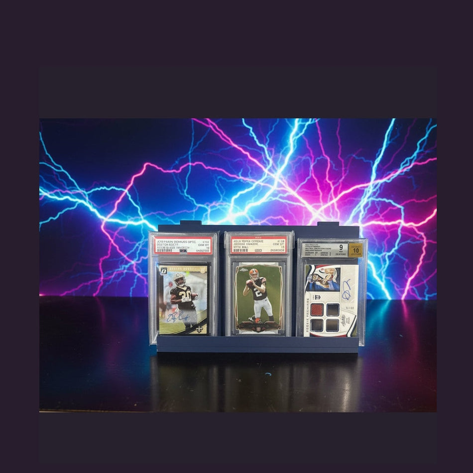 Collection of sports trading cards in protective cases on a dark surface.
