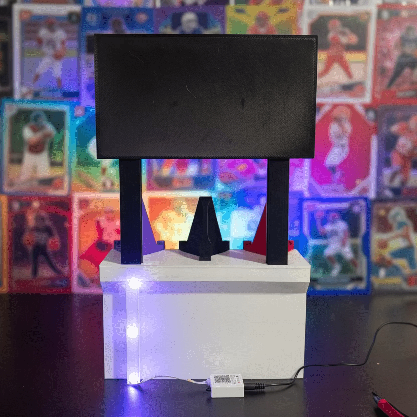 Small black monitor on a white stand with colorful accents on a dark surface.