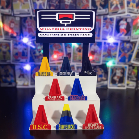 Colorful 3D-printed traffic cone models with branding in front of a 3D printer.