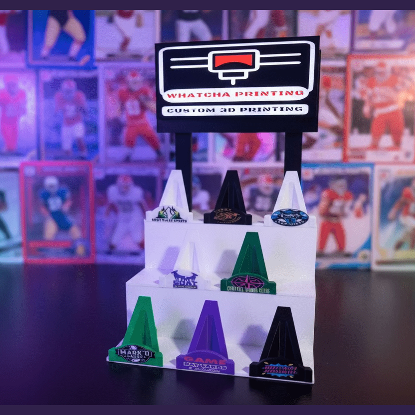 Display of 3D-printed objects with a 'Whatcha Printing' sign in the background