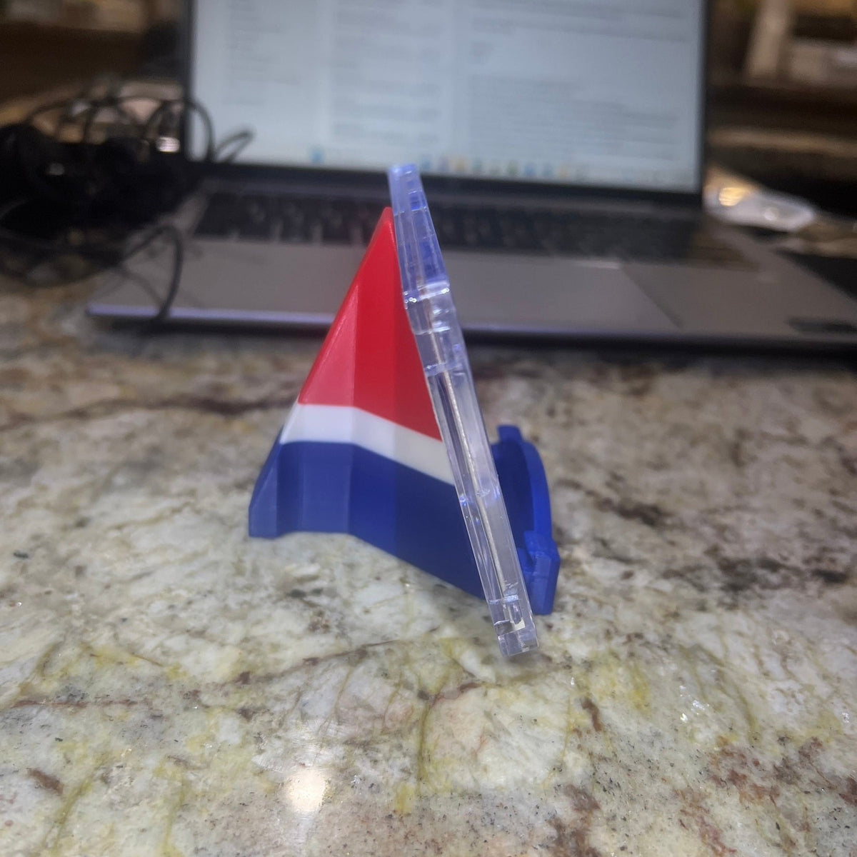 Colorful plastic triangle on a marble surface with a laptop in the background