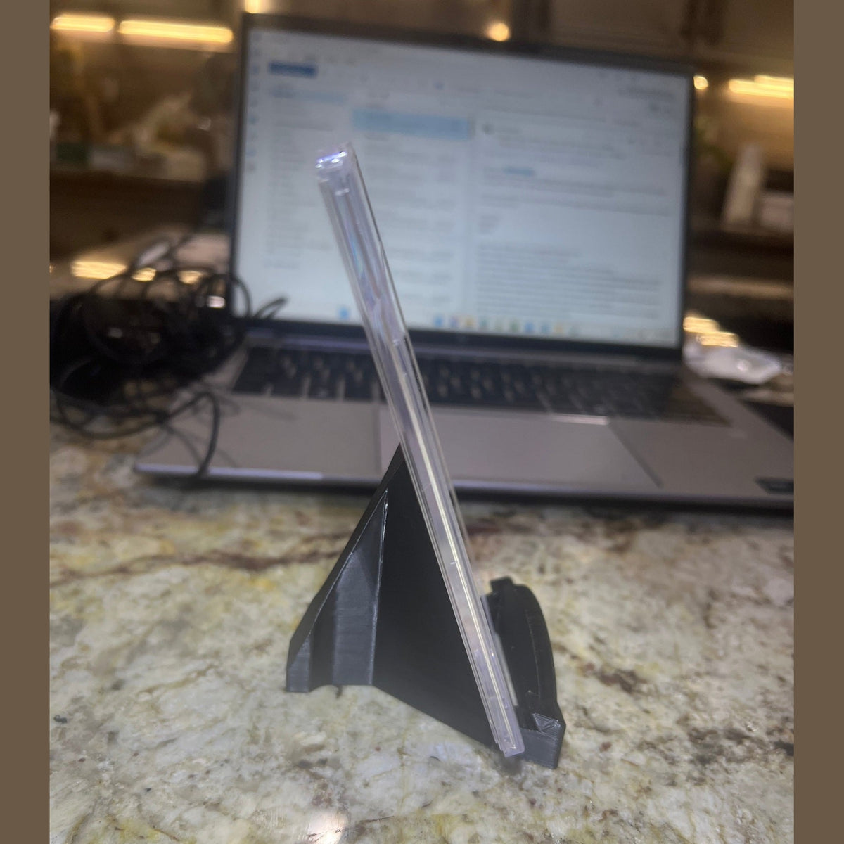Clear plastic straw on a marble surface with a laptop in the background