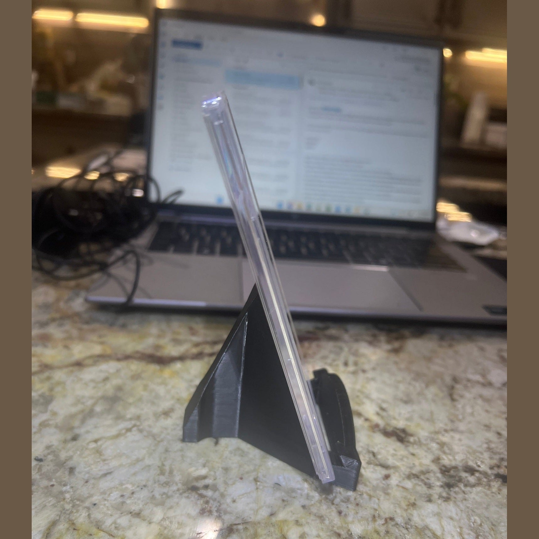 Clear plastic straw on a marble surface with a laptop in the background
