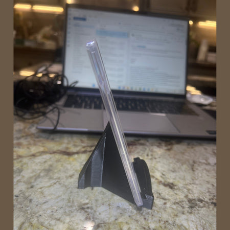 Clear plastic straw on a marble surface with a laptop in the background