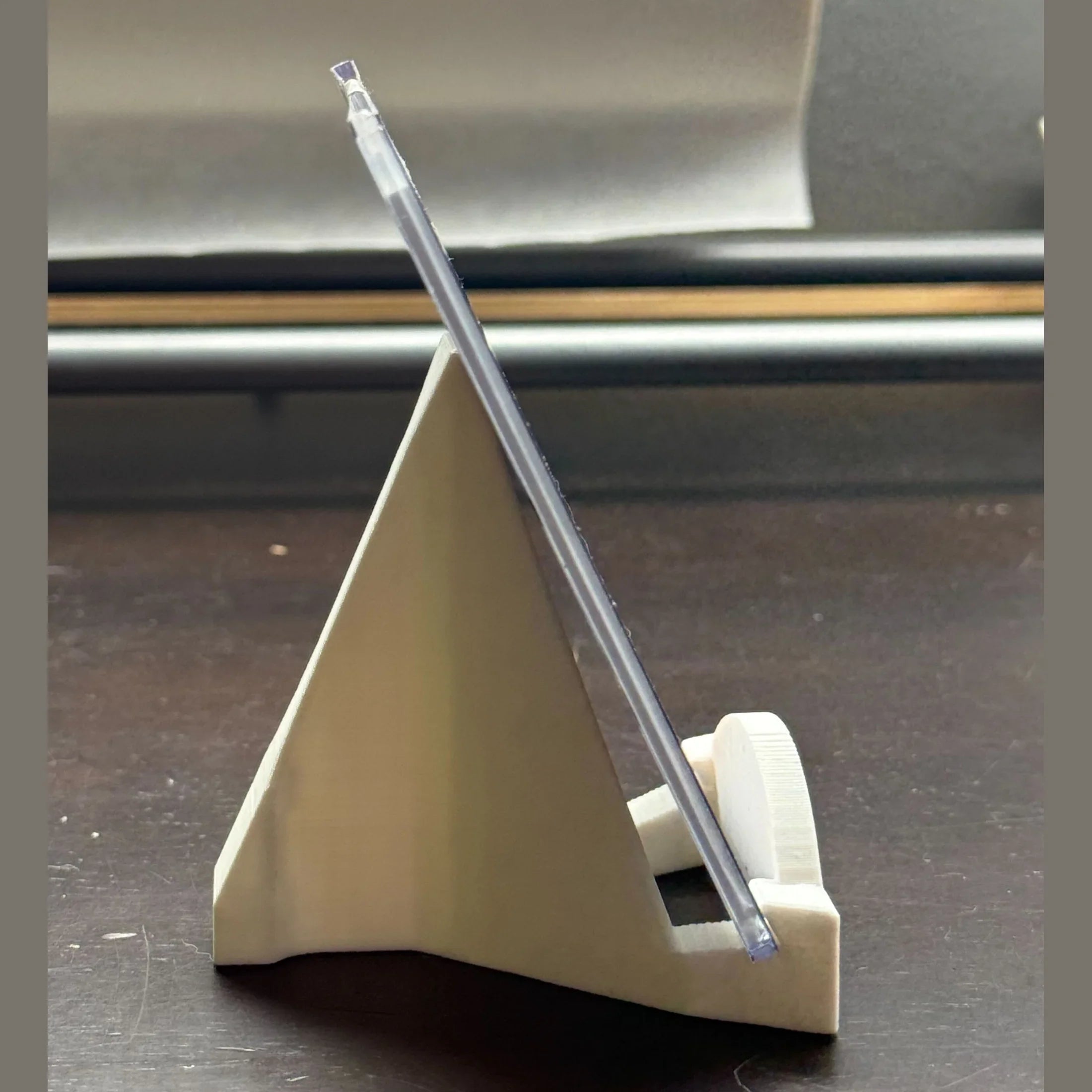 Clear straw in a beige holder on a dark surface