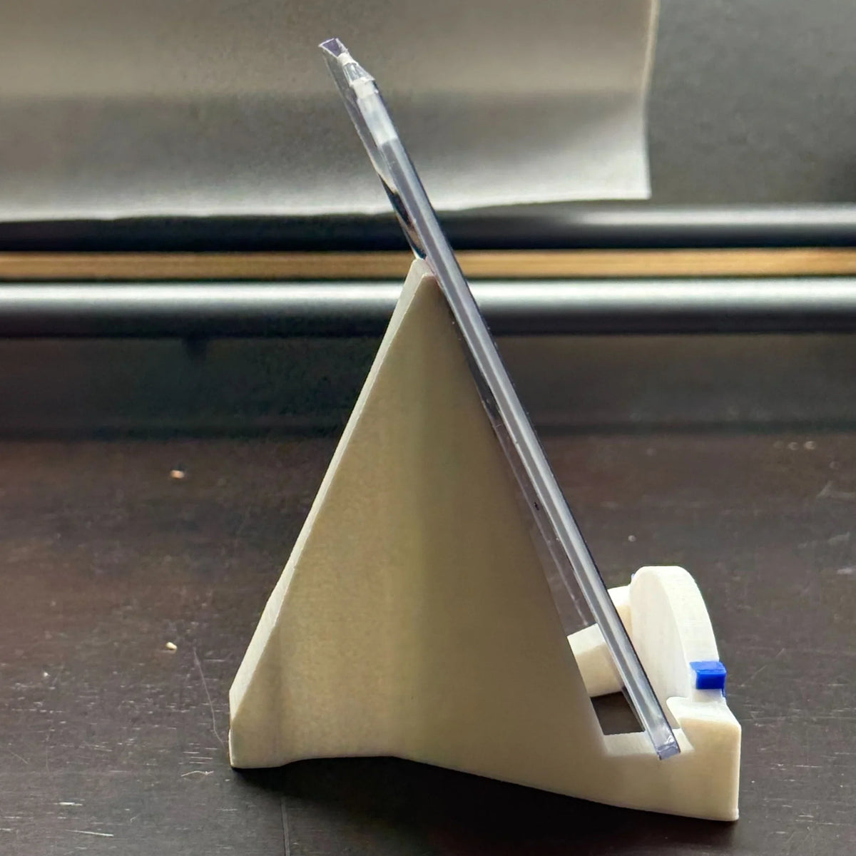 Clear plastic tool on a beige stand with a metallic background