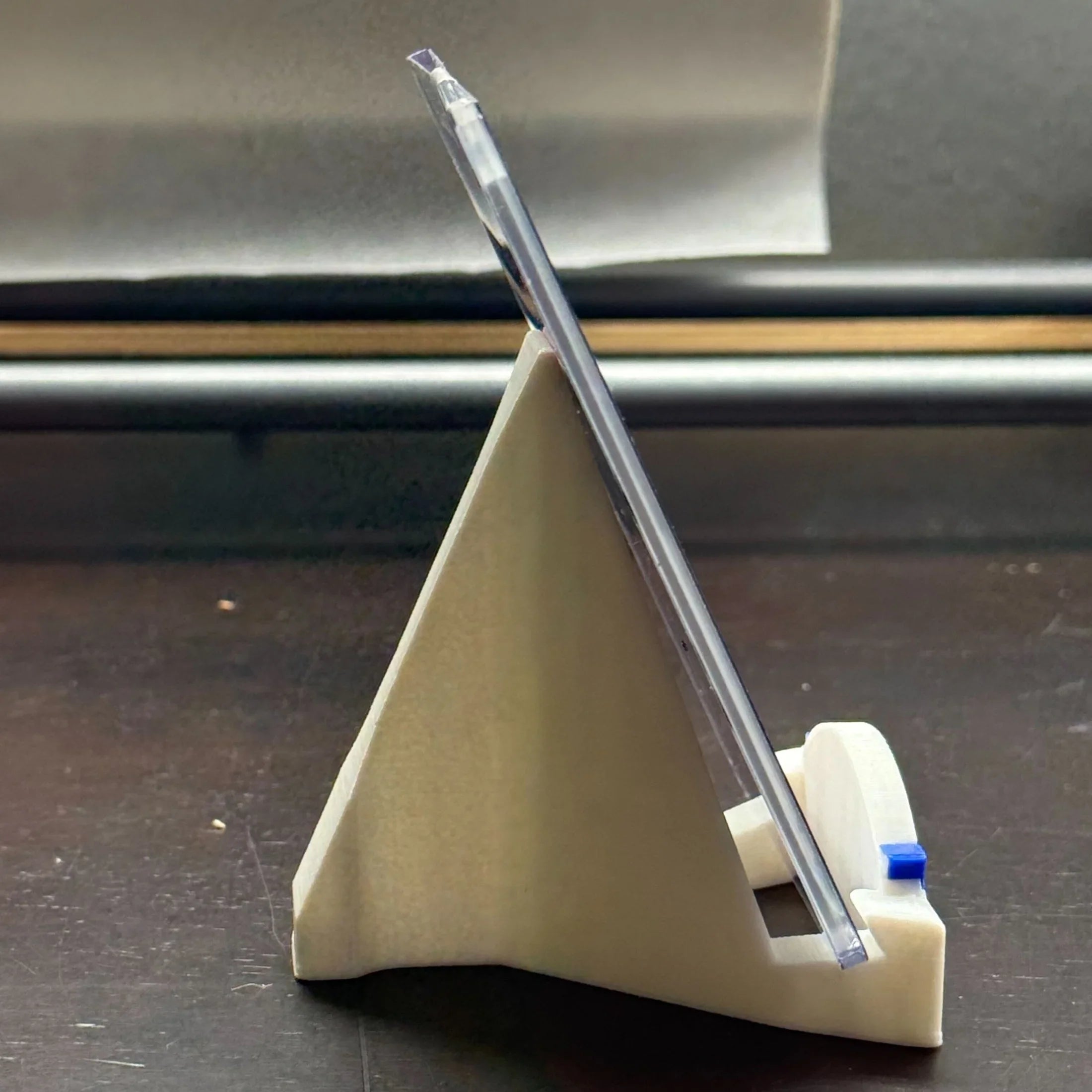 Clear plastic tool on a beige stand with a metallic background