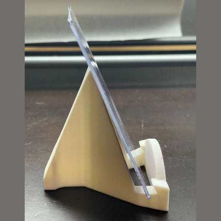 Clear plastic tool on a beige stand against a dark background