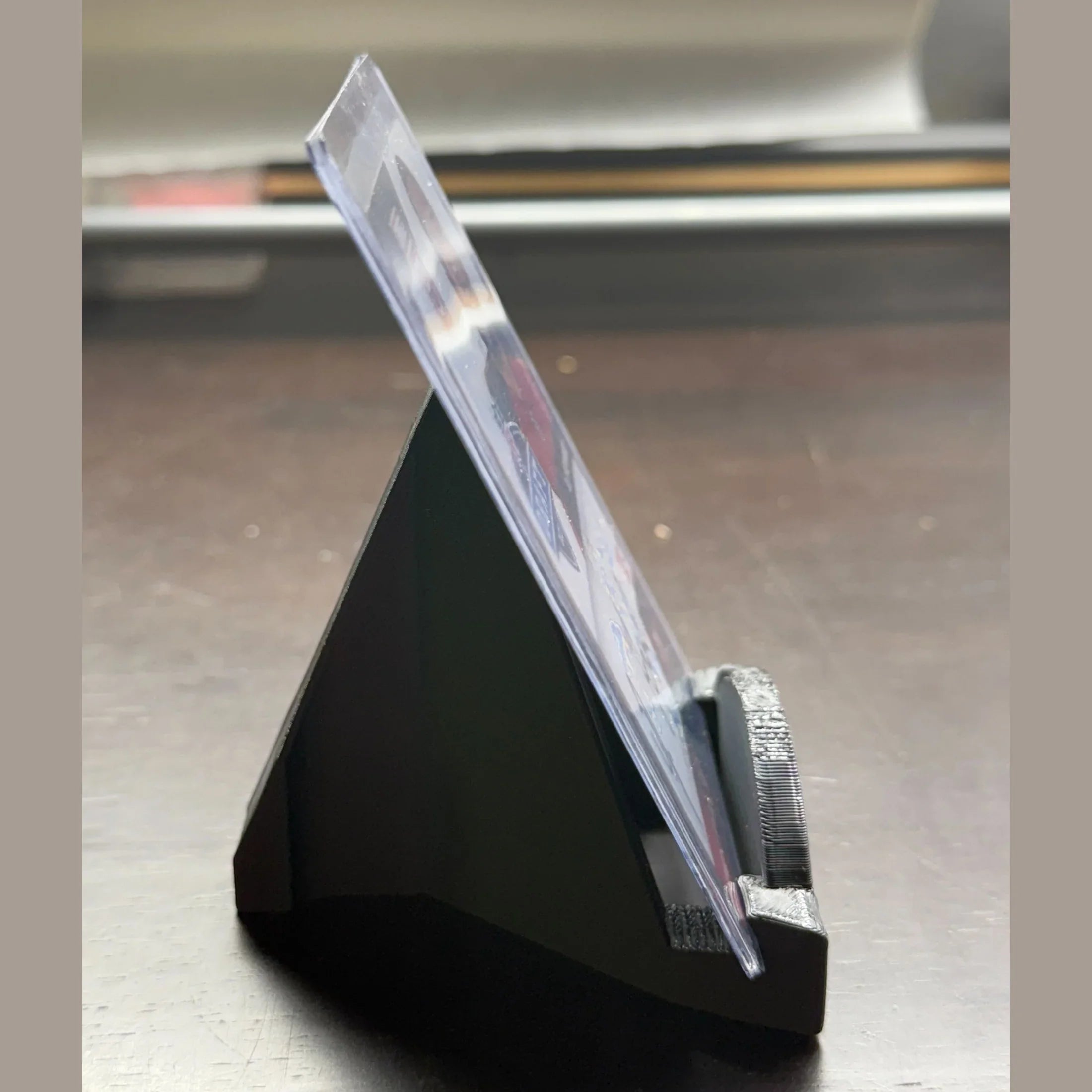 Black triangular stand with a clear acrylic panel on a wooden surface