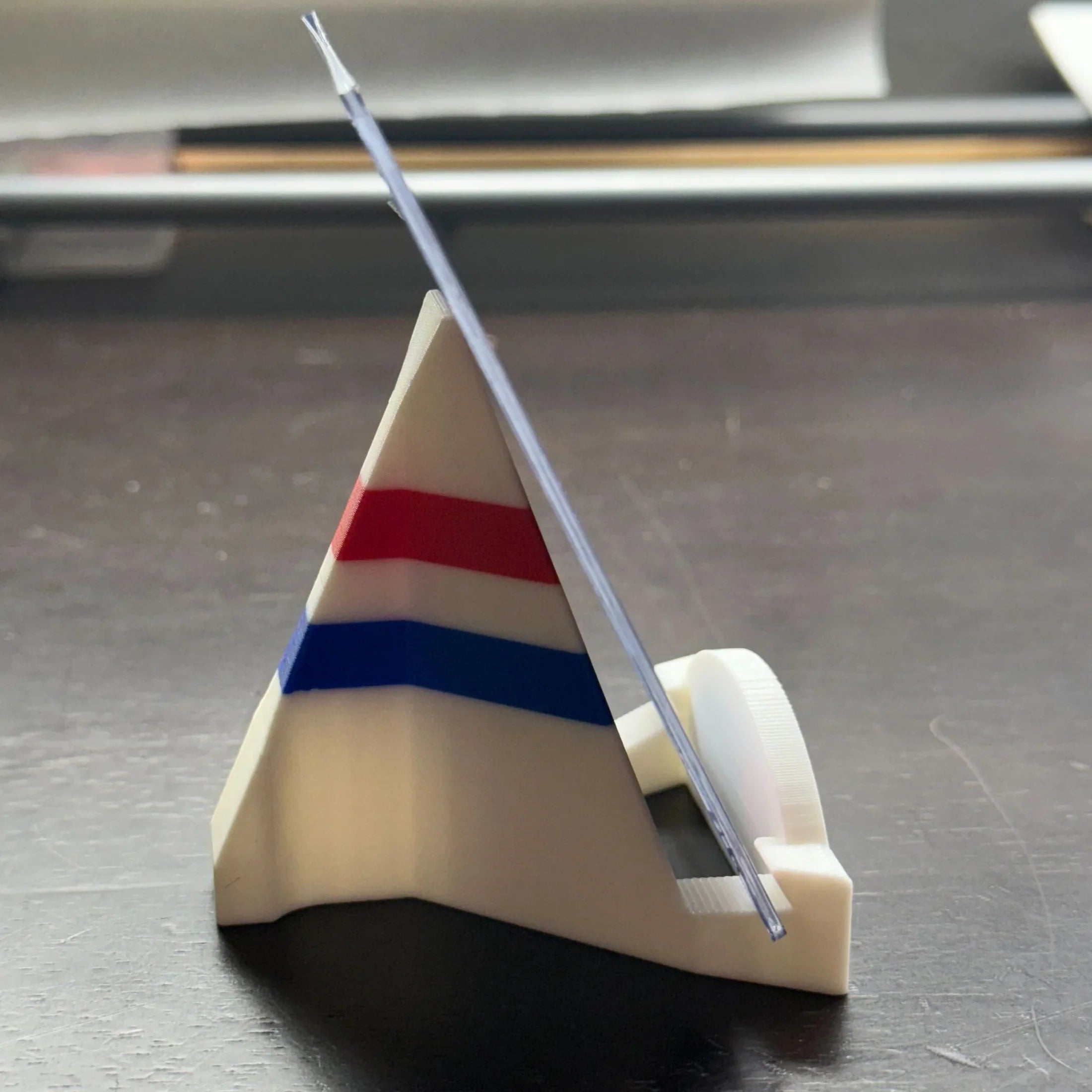 Triangular stand with a clear rod on a dark surface