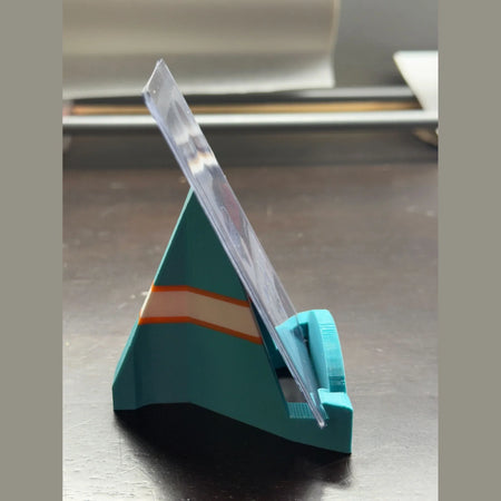 Teal paper cutter with clear blade on a metallic surface