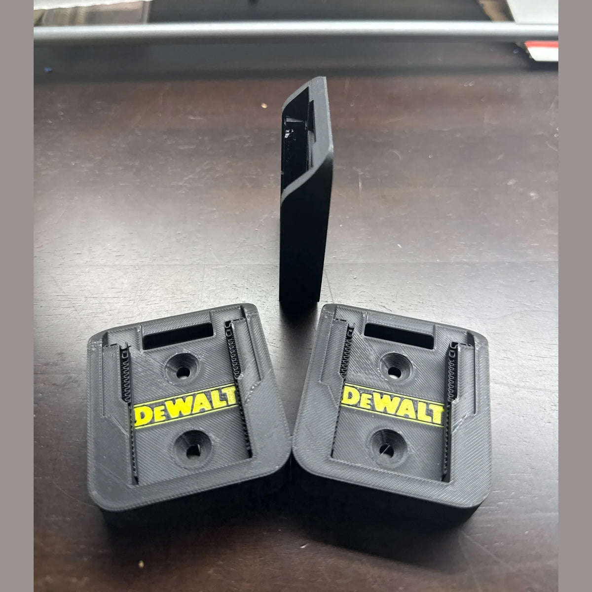 Two DEWALT tool attachments on a metallic surface
