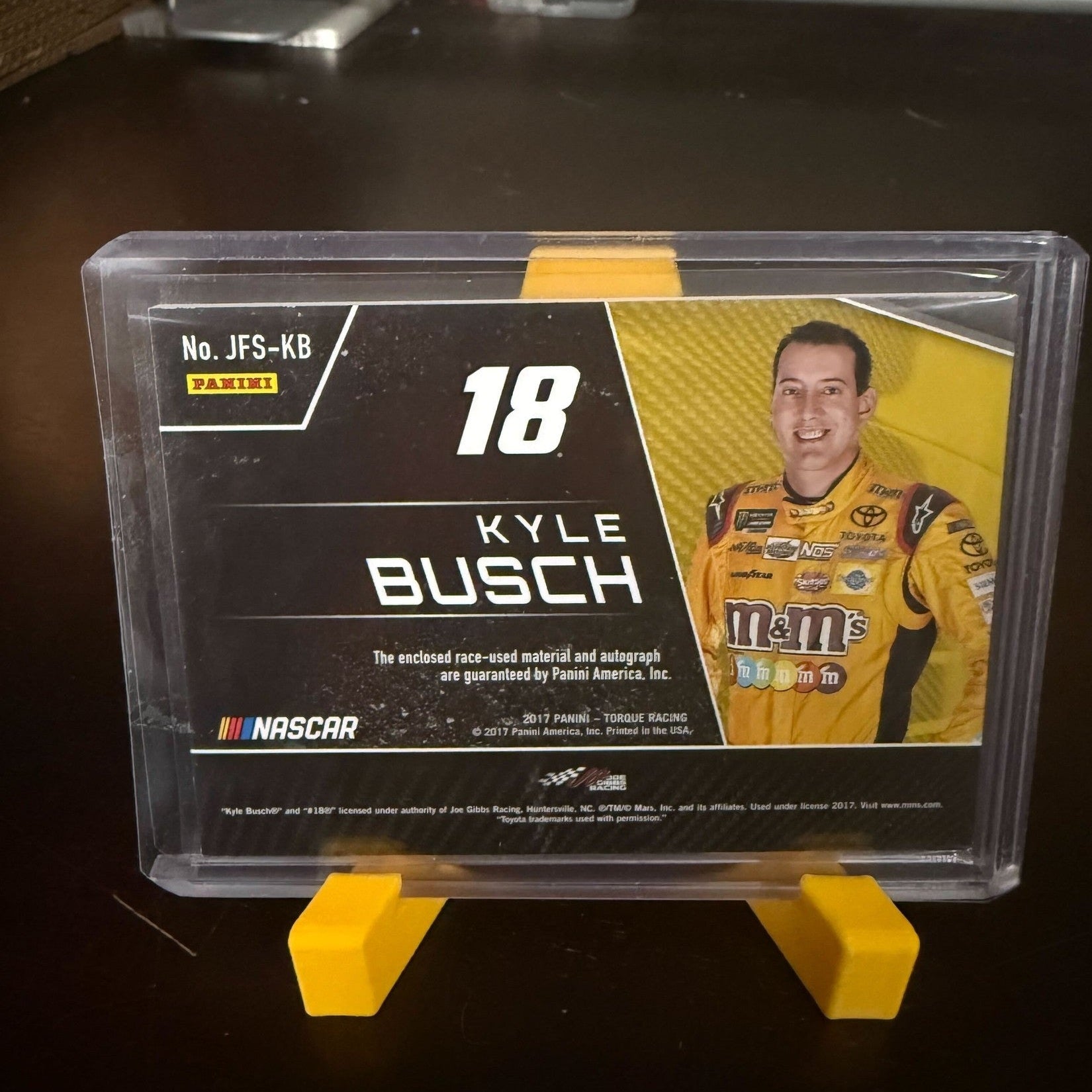 Trading card of Kyle Busch in a clear holder with yellow stand