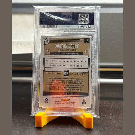 Trading card of Boston Scott from the New Orleans Saints on a yellow card holder with a clear protective case.