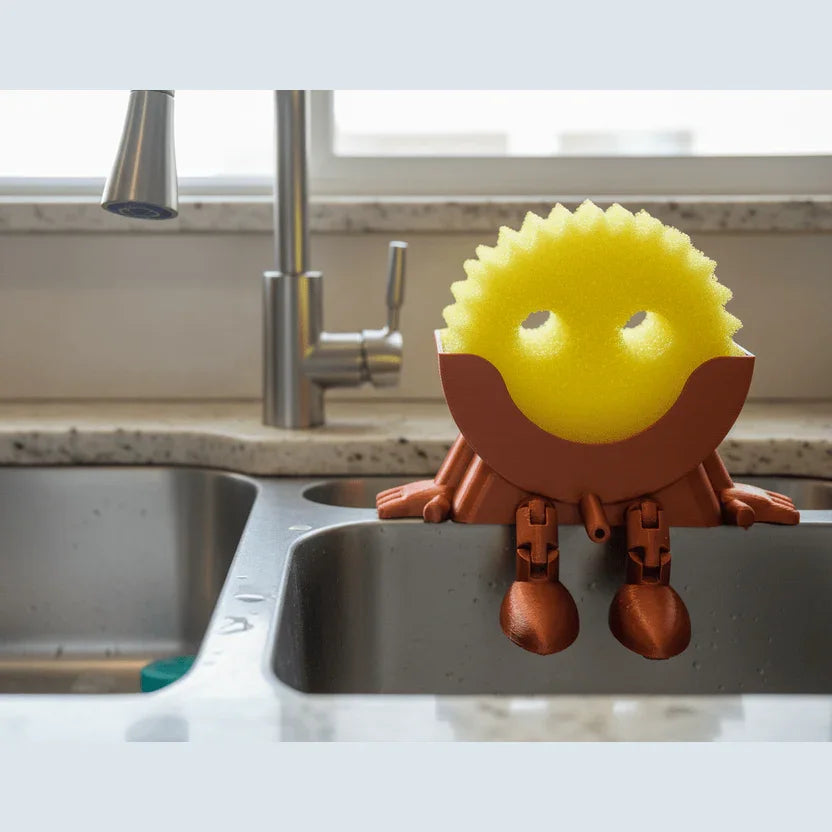 Yellow sponge with brown holder on a kitchen sink