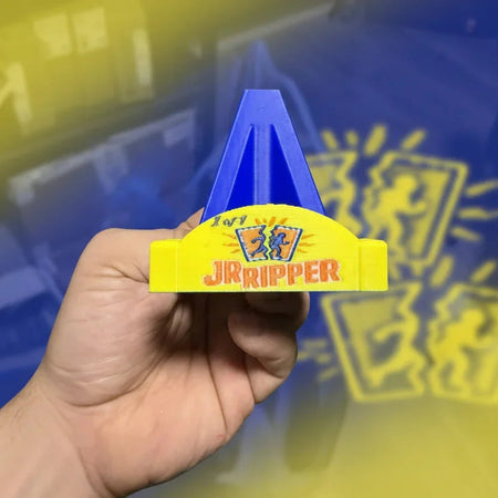 Hand holding a blue and yellow tool labeled 'JR Ripper' in an indoor setting.