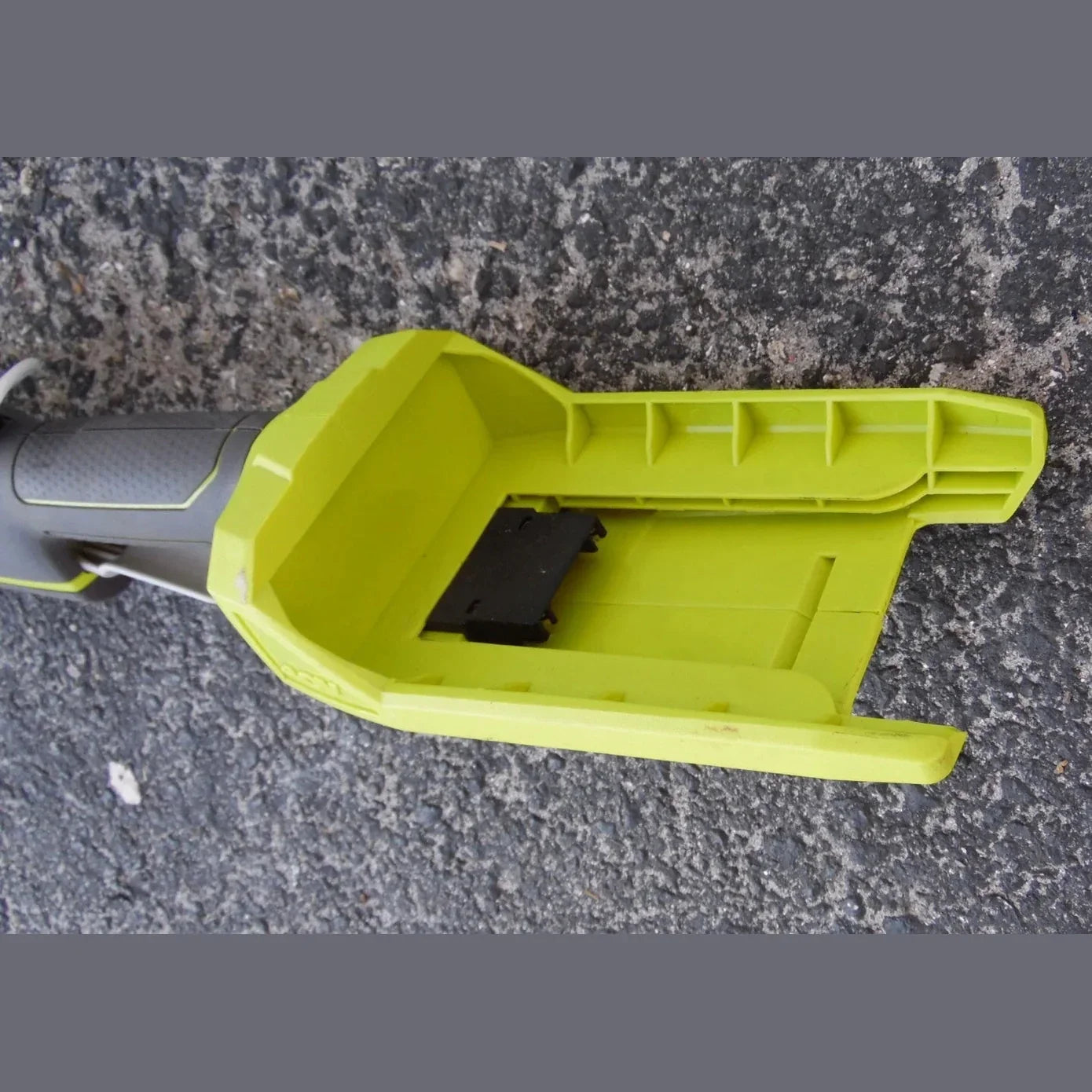 Green battery cover of a power tool on a gray surface