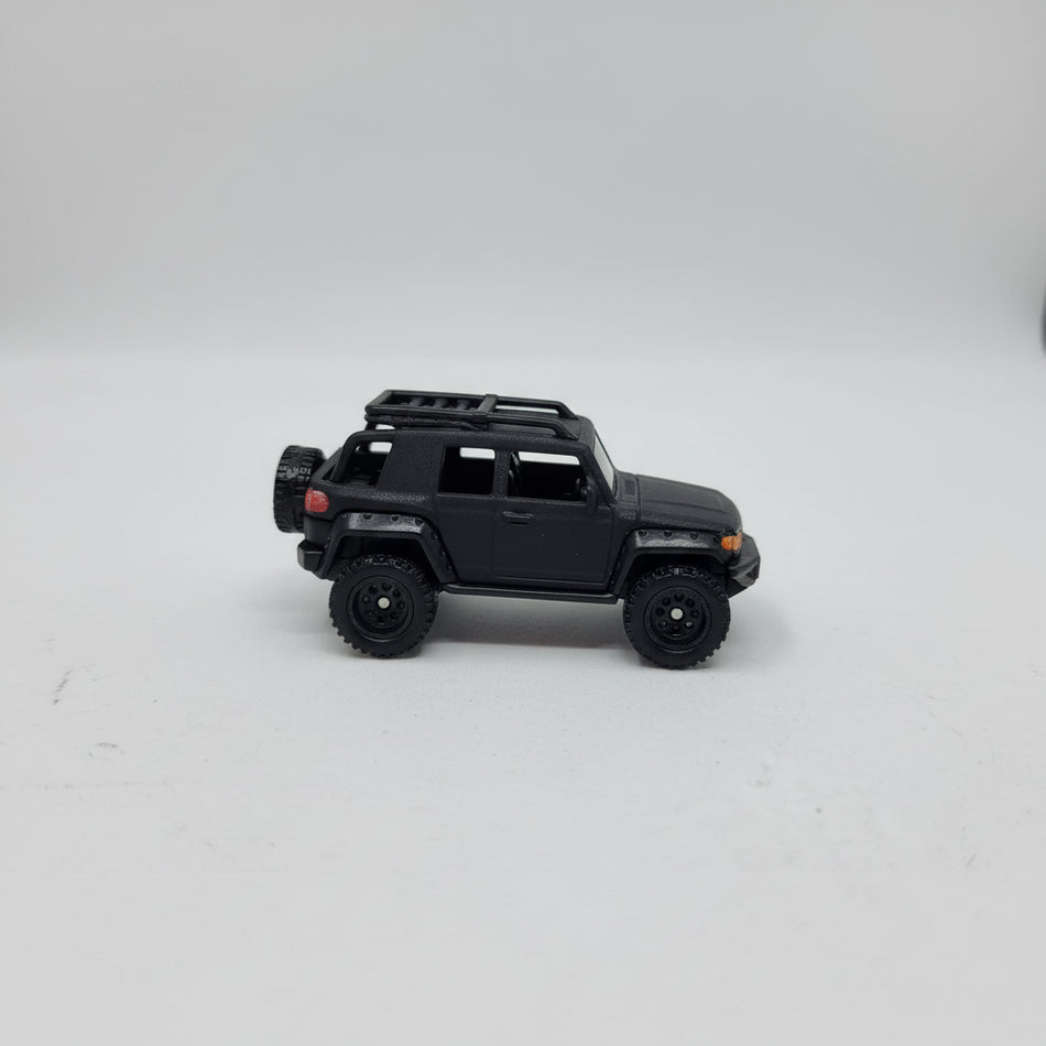 Black toy truck in clear packaging on a white surface