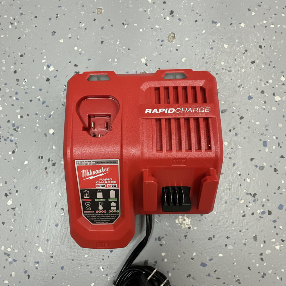 Red Milwaukee rapid charge battery pack on a speckled gray surface