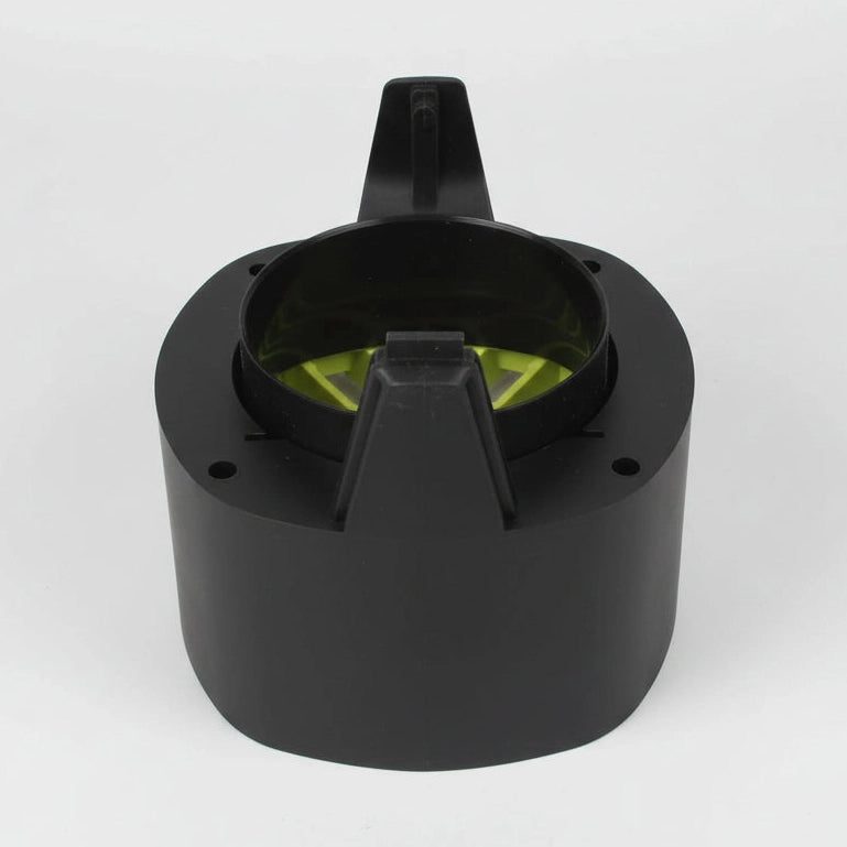 Black plastic component with green interior on a white floor